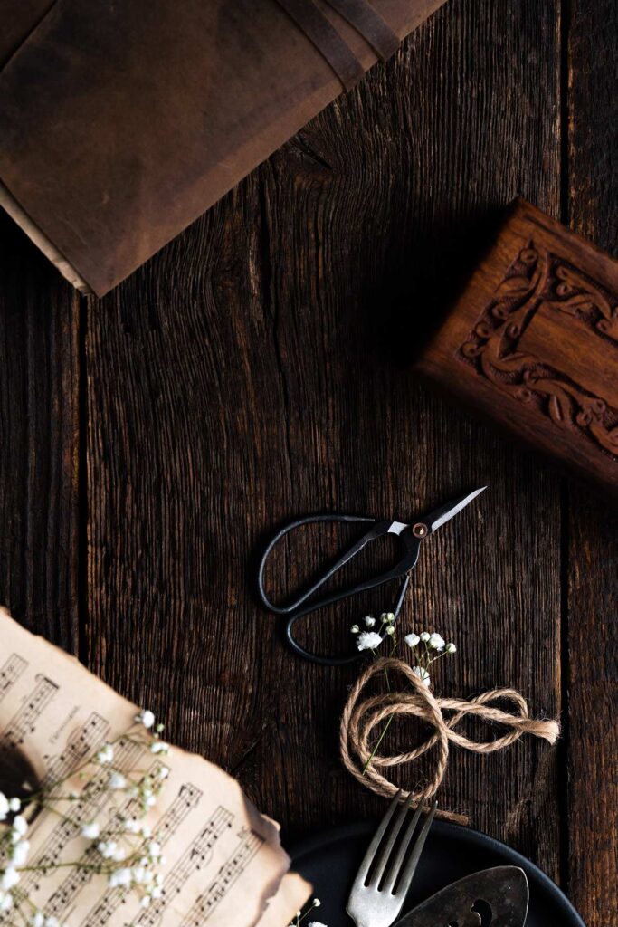 rustic dark wooden table with vintage books music sheets and scissors