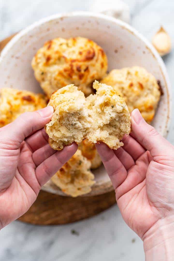 hands pulling apart garlic bread drop biscuit to show fluffy interior