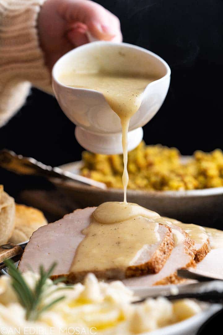 pouring gravy from gravy boat onto turkey breast on plate