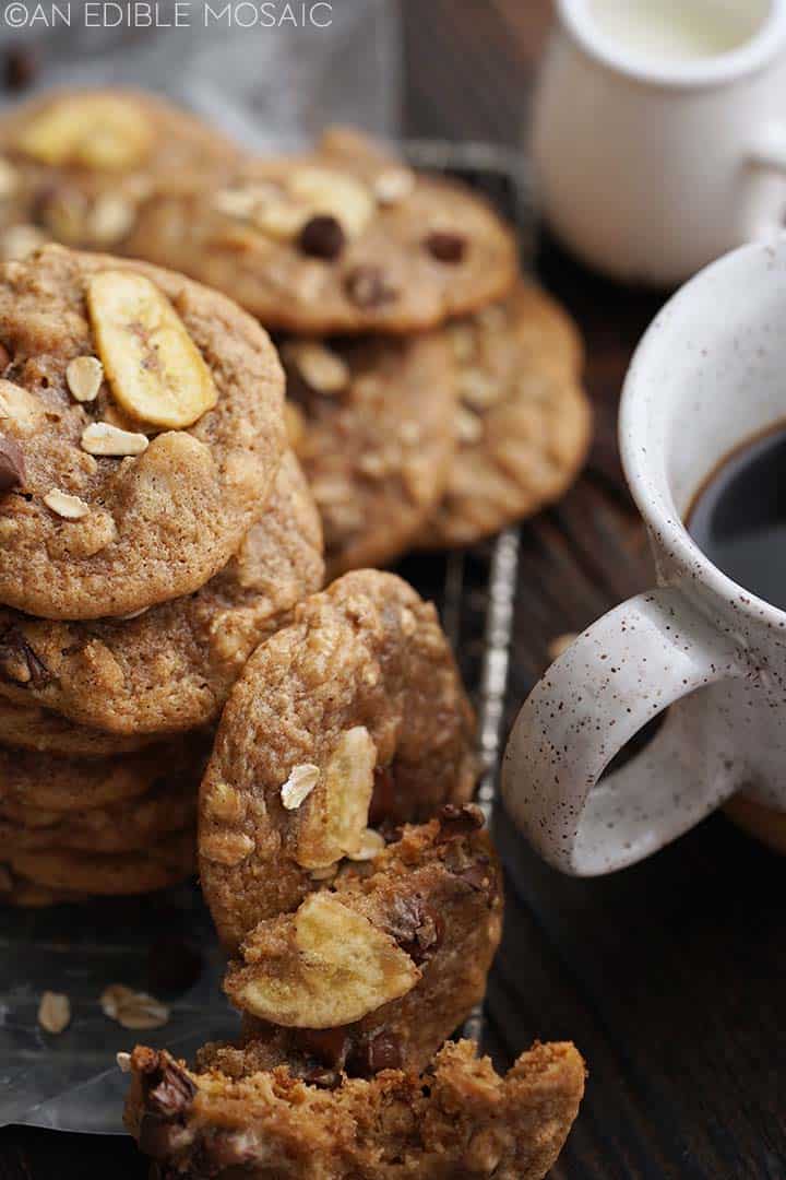 stack of banana bread cookies with broken cookies in front next to mug of coffee