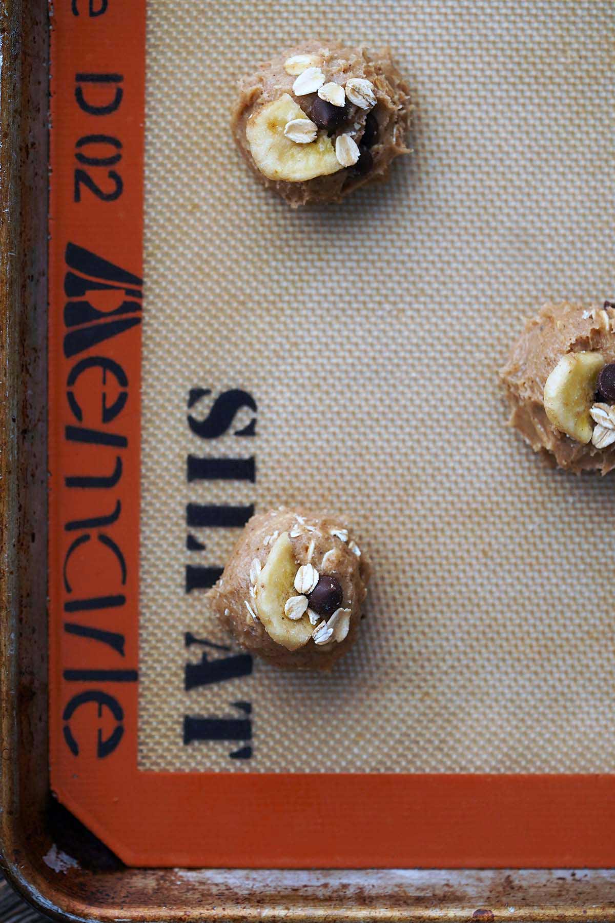 banana bread chocolate chip cookies before baking on sillpat liner on baking tray