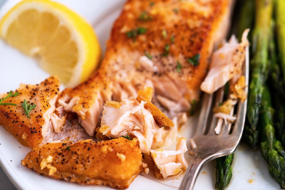 close up of tender flaky pan fried garlic lemon butter salmon on serving plate