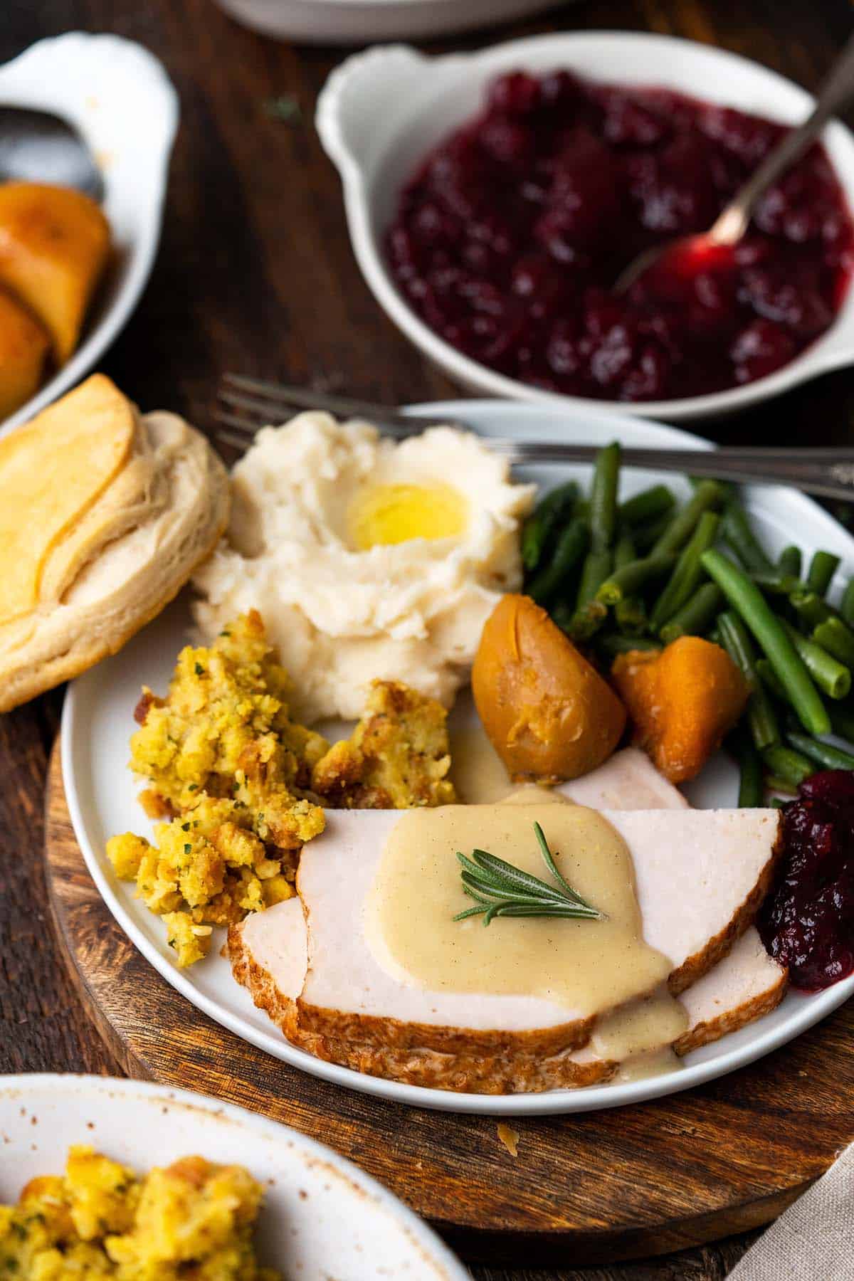 thanksgiving dinner plate with turkey and fixings on table with side dishes