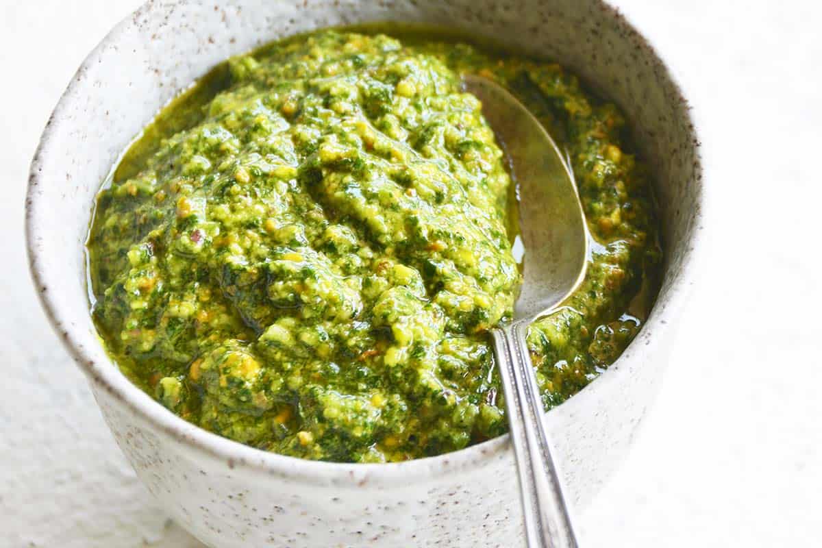 close up view of cilantro pesto with spoon in bowl