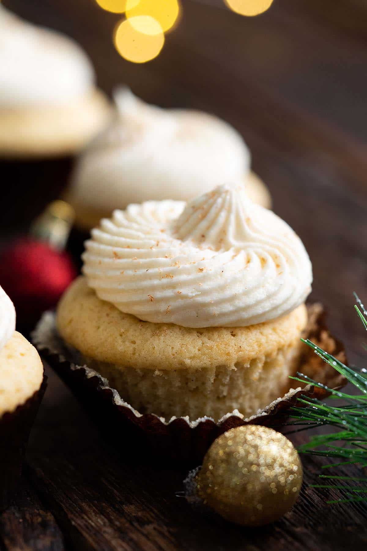 eggnog cupcake partially unwrapped with festive lights in background