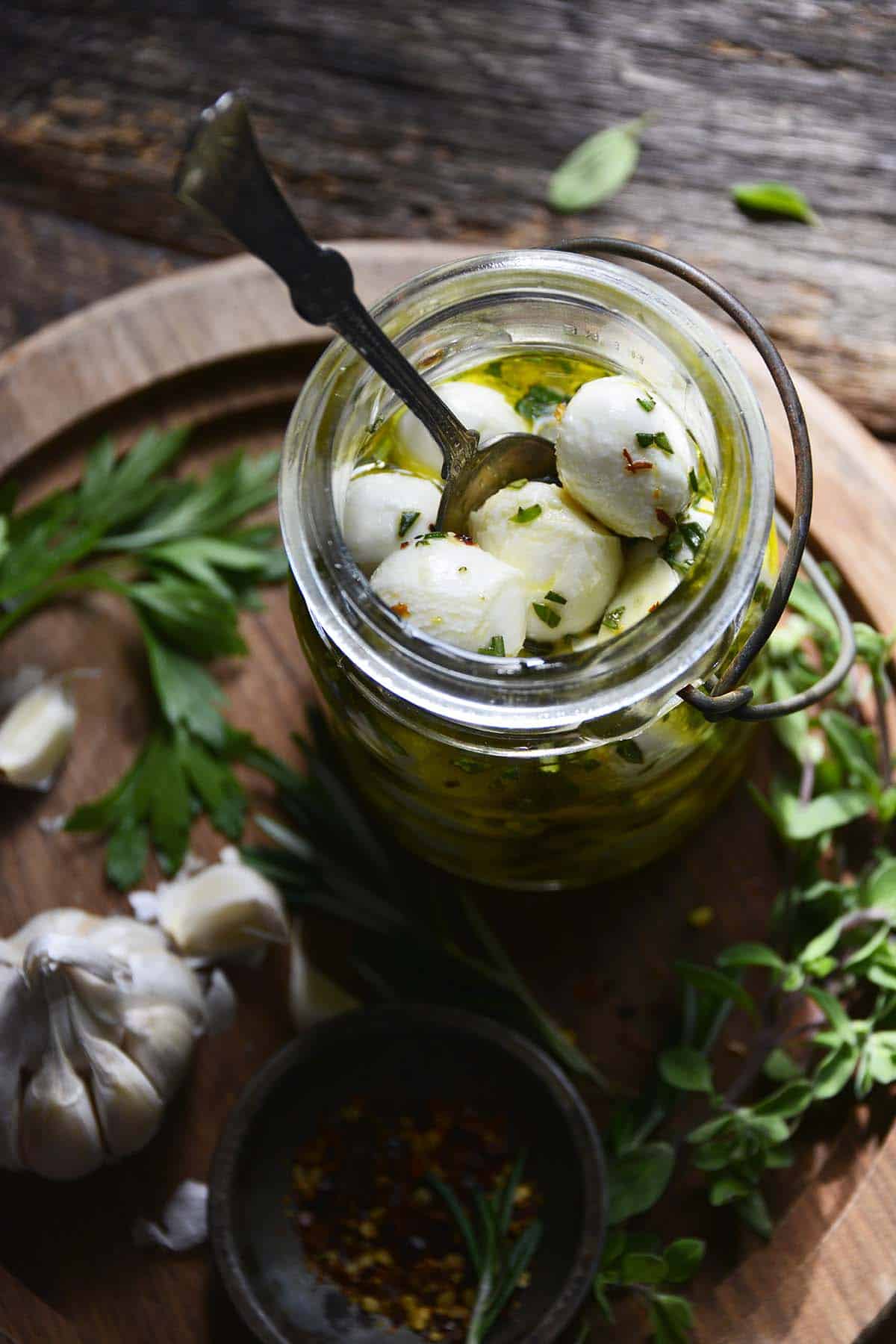 glass jar with mozzarella balls and aromatics