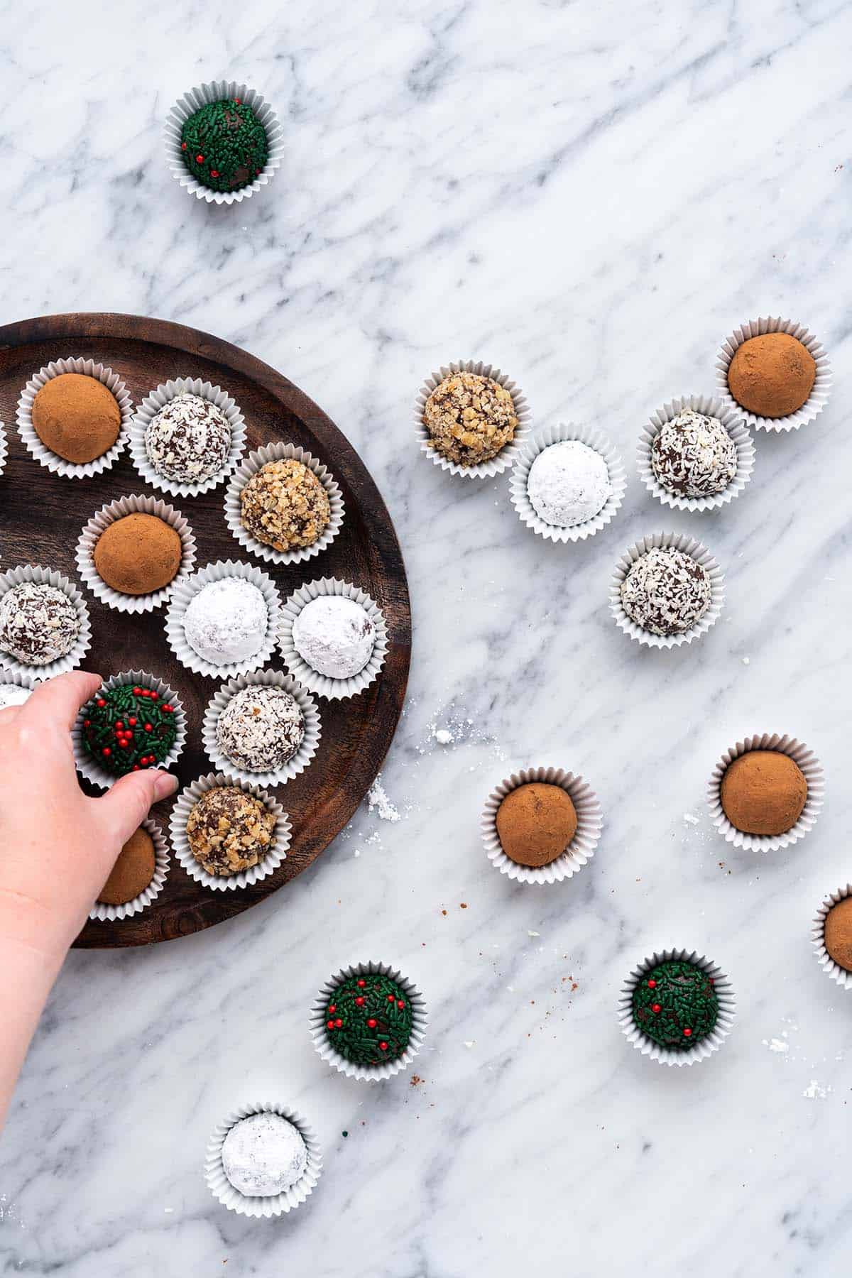 hand reaching in to grab rum ball off holiday platter