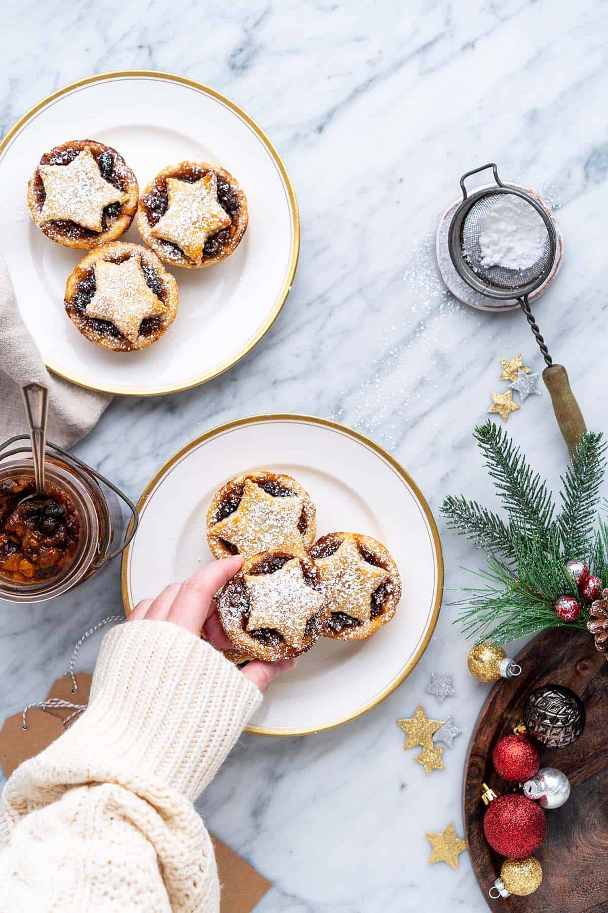 hand reaching in to take mincemeat tart off plate