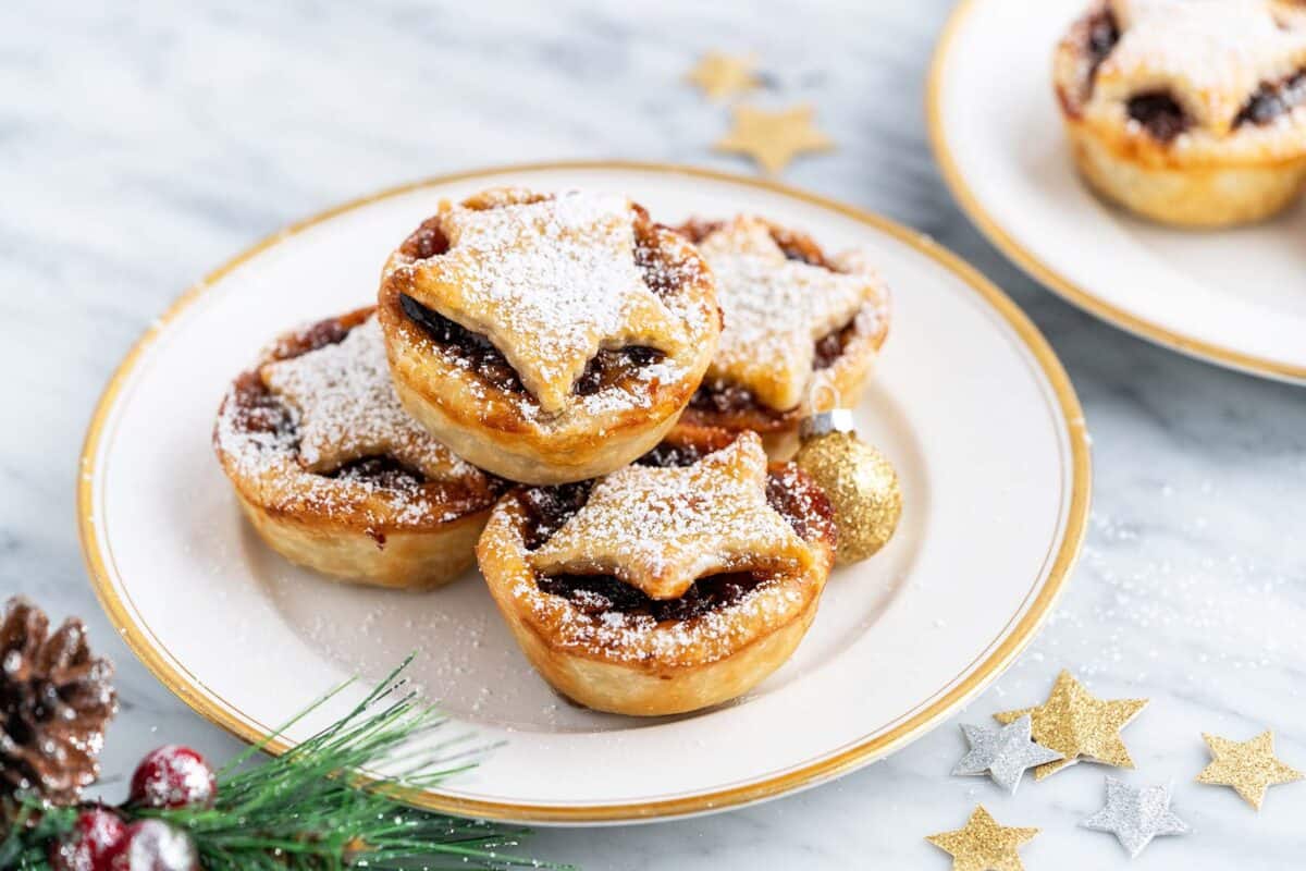 stacked mince tarts on plate with christmas bough in front