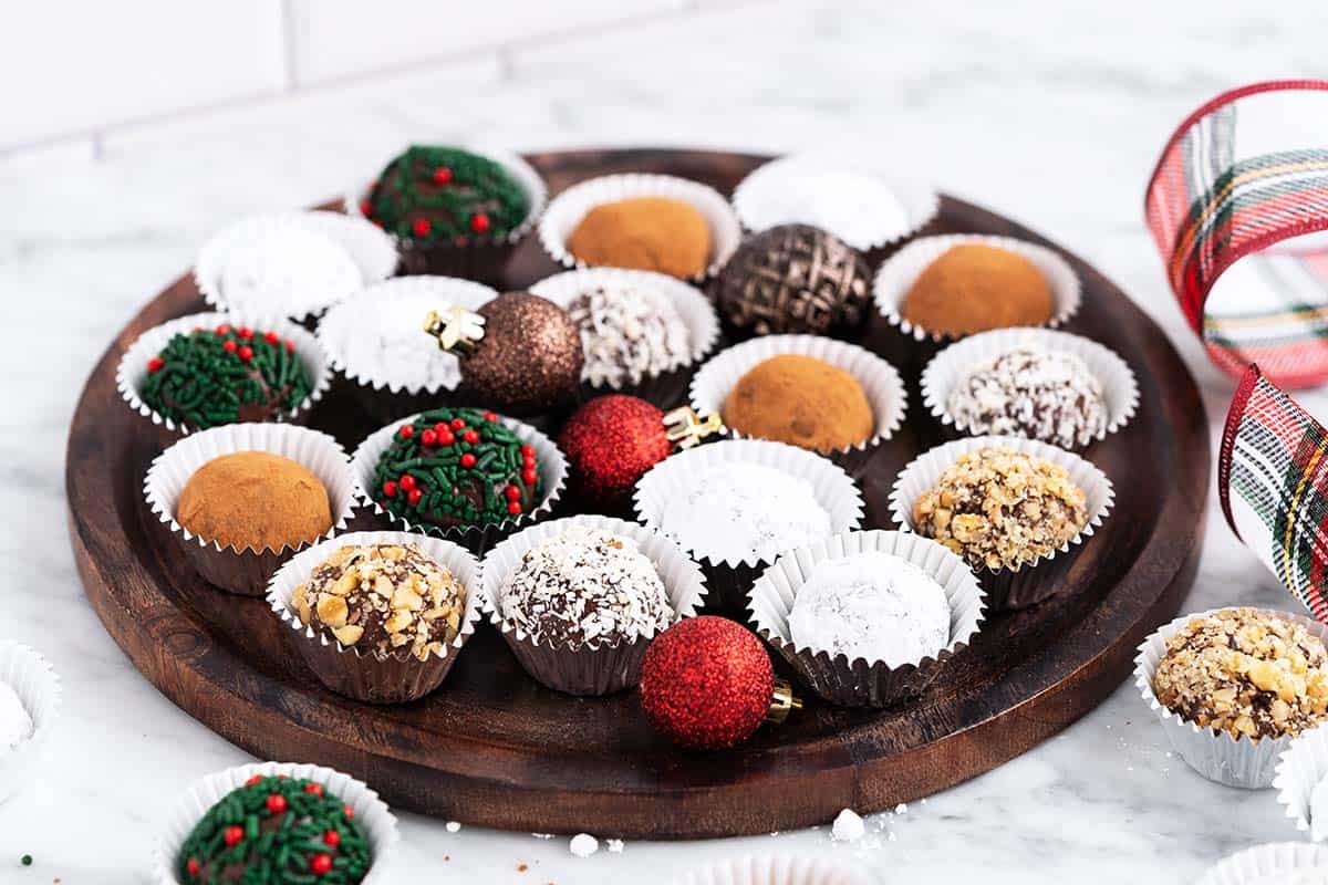 wooden platter with rum balls and festive christmas ornaments on marble countertop