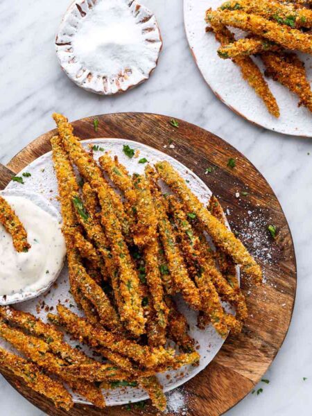 air fryer green bean fries on white plat eon top of wooden board on marble countertop