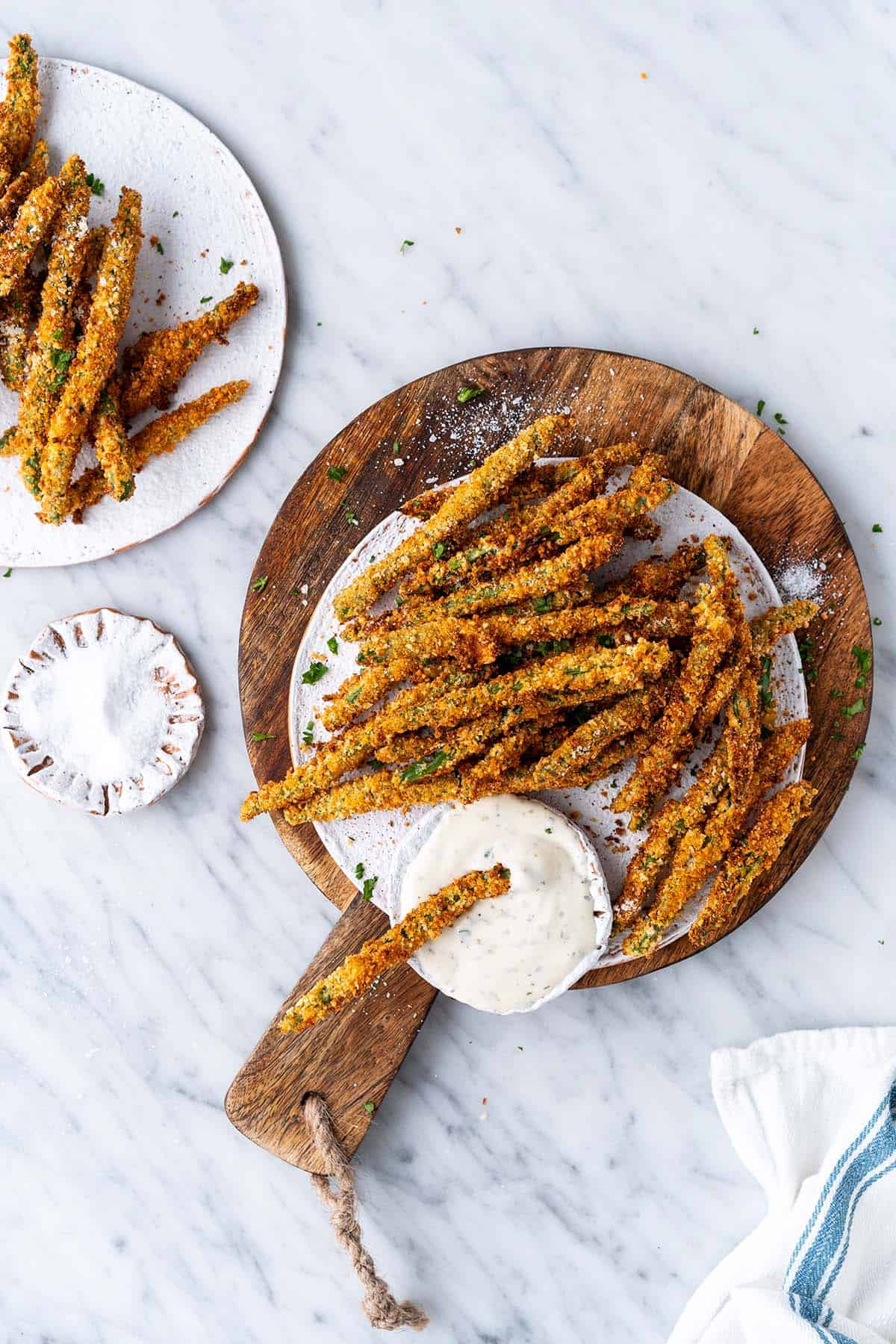 air fryer green bean fries on white plate on top of wooden board