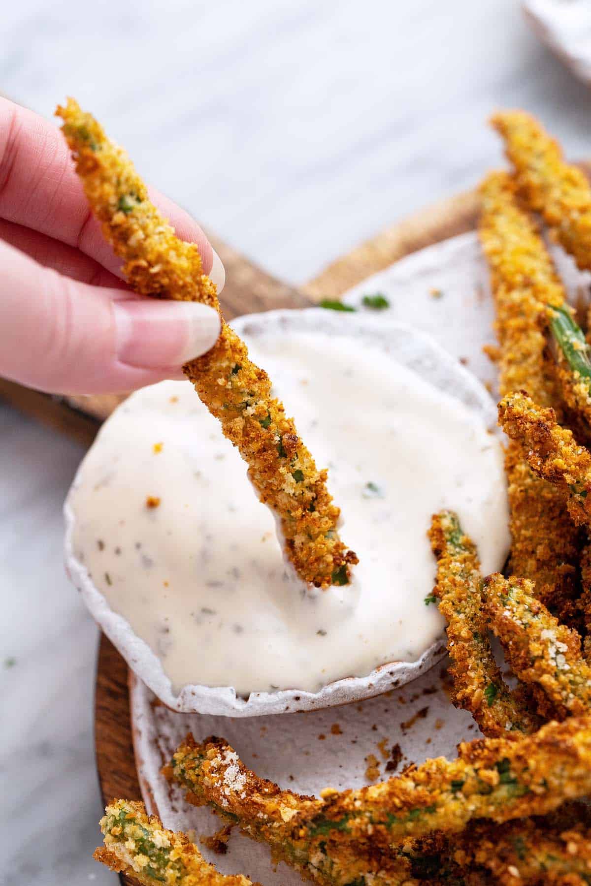 hand dipping green bean fry into ranch dressing
