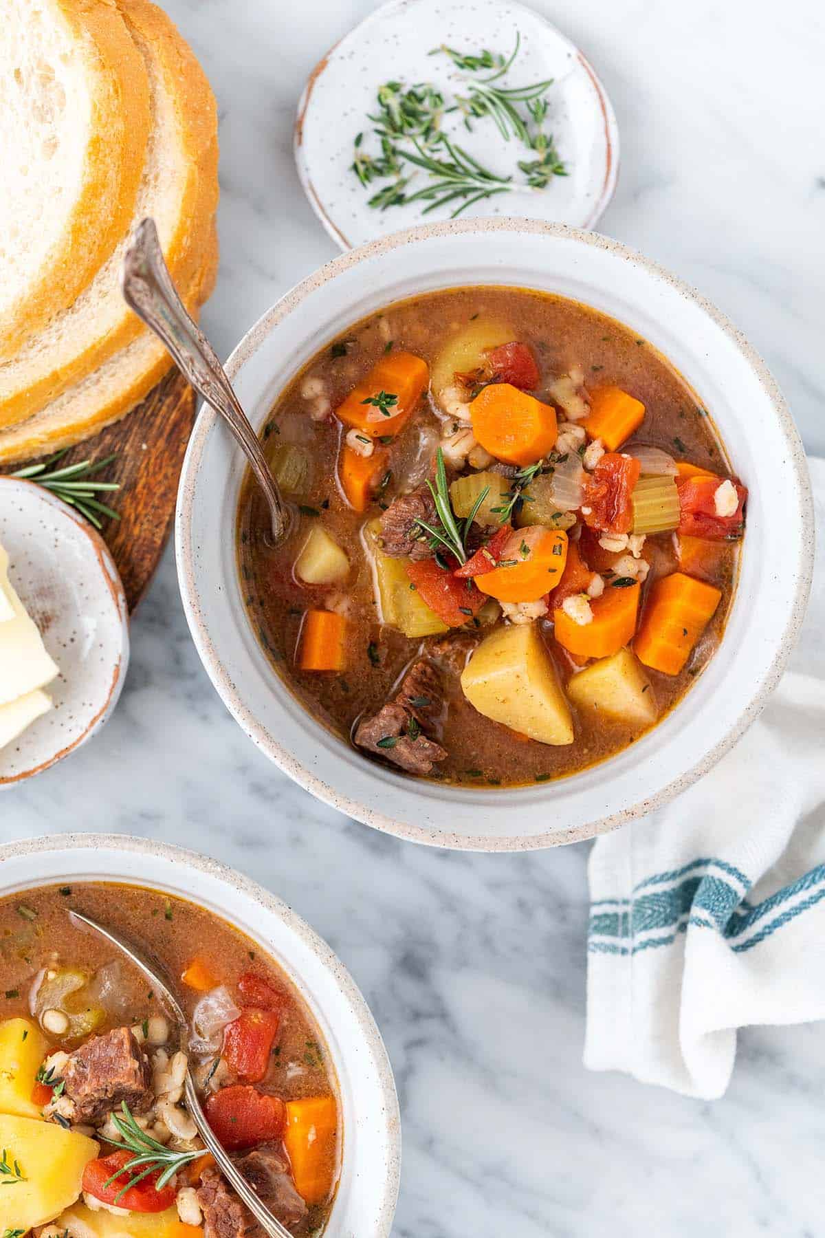 overhead view of barley beef soup in bowls with fresh sliced bread