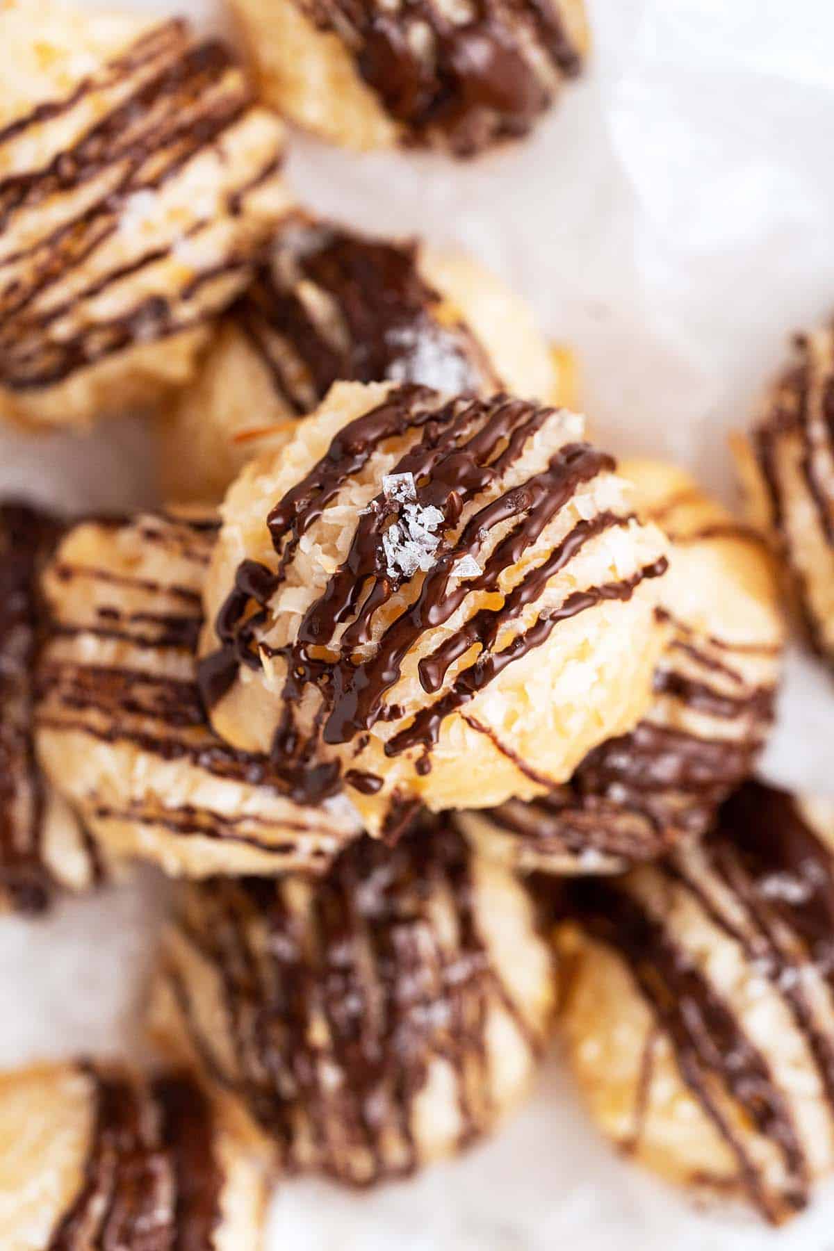 overhead view of pile of coconut macaroons with chocolate drizzle and flaky sea salt