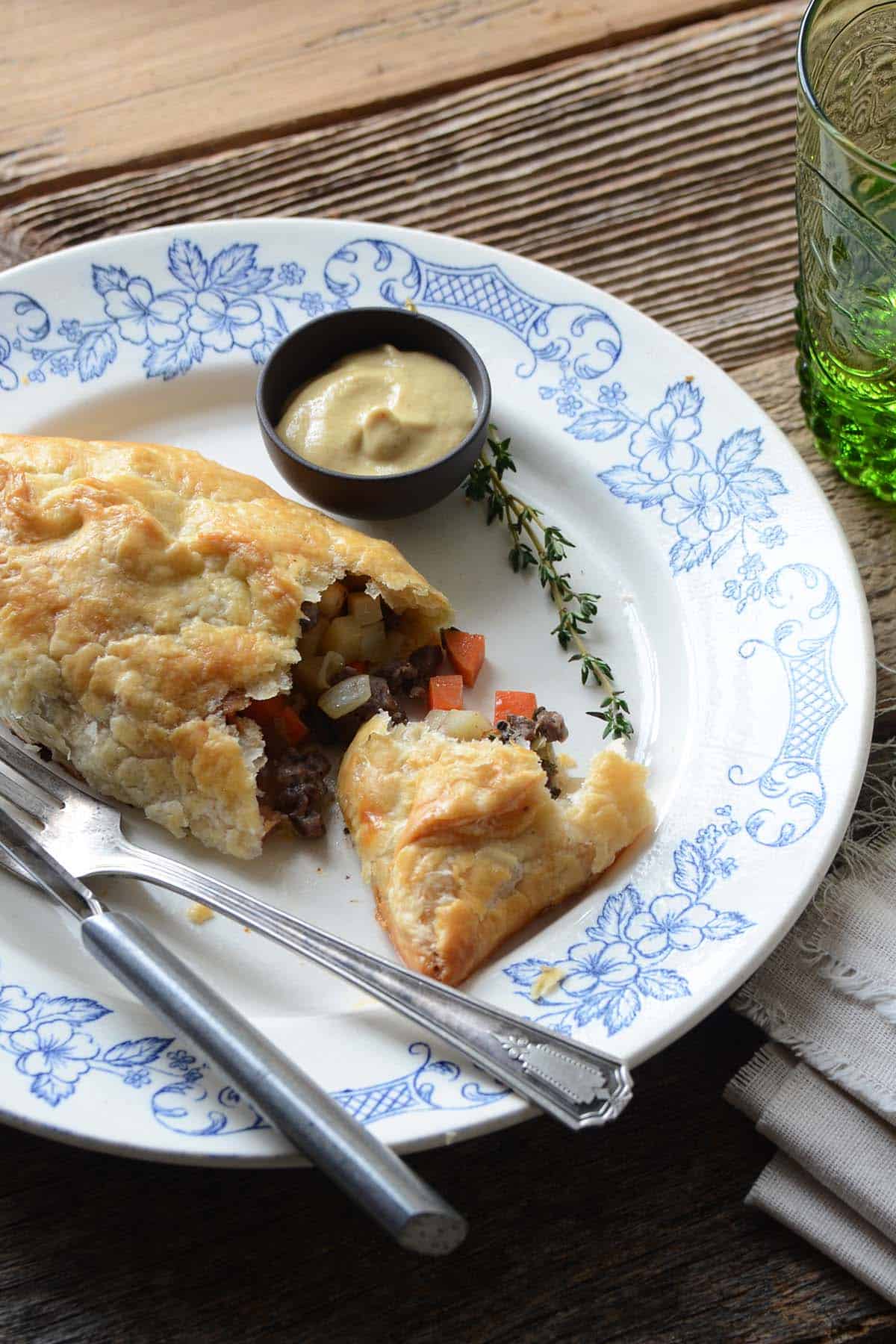 close up of meat pasty on plate cut open to show beef vegetable filling