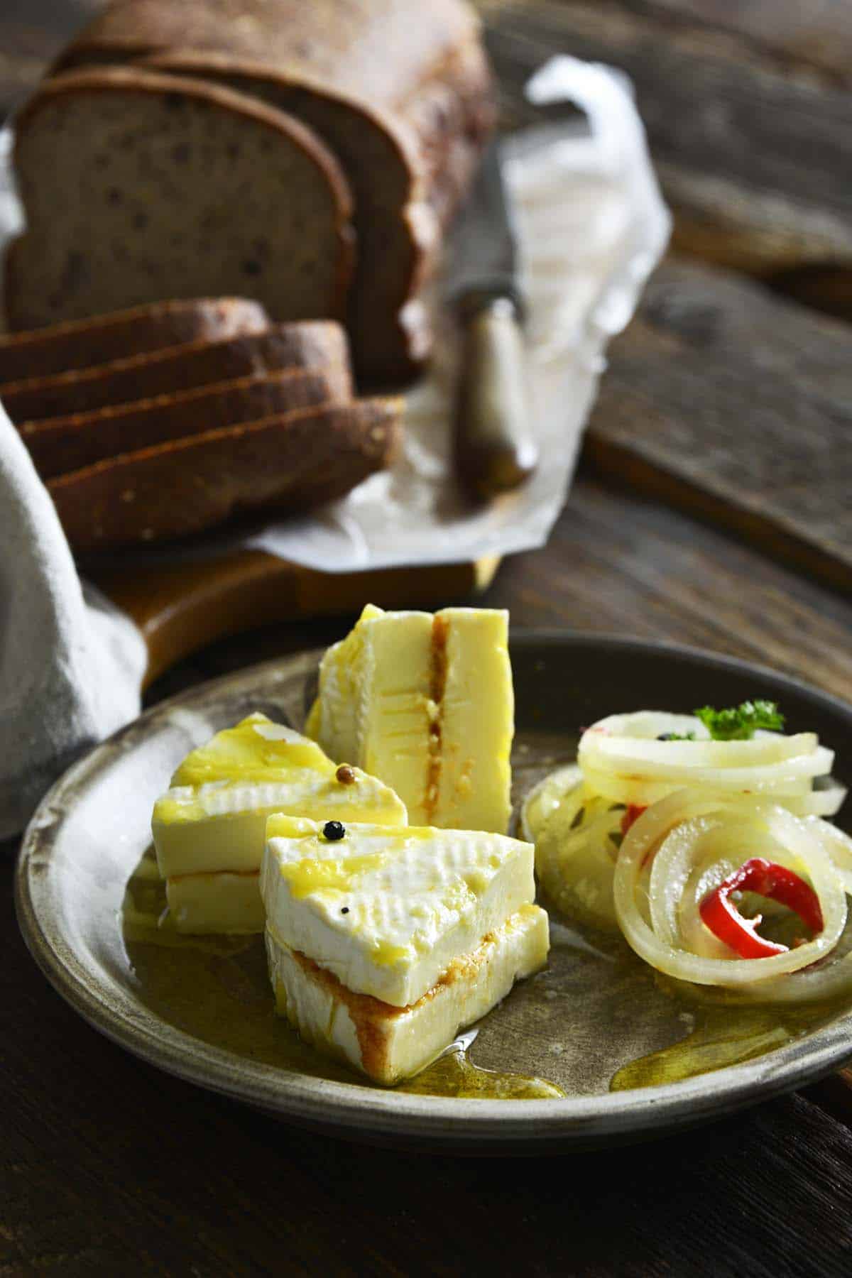 czech marinated cheese on czech pottery w ith loaf of sliced bread in background