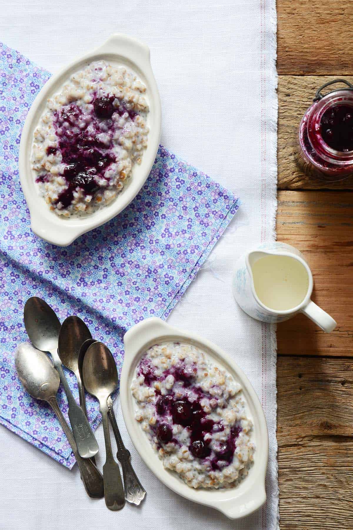 dishes of vegan wheat berry porridge with blueberry ginger sauce on top
