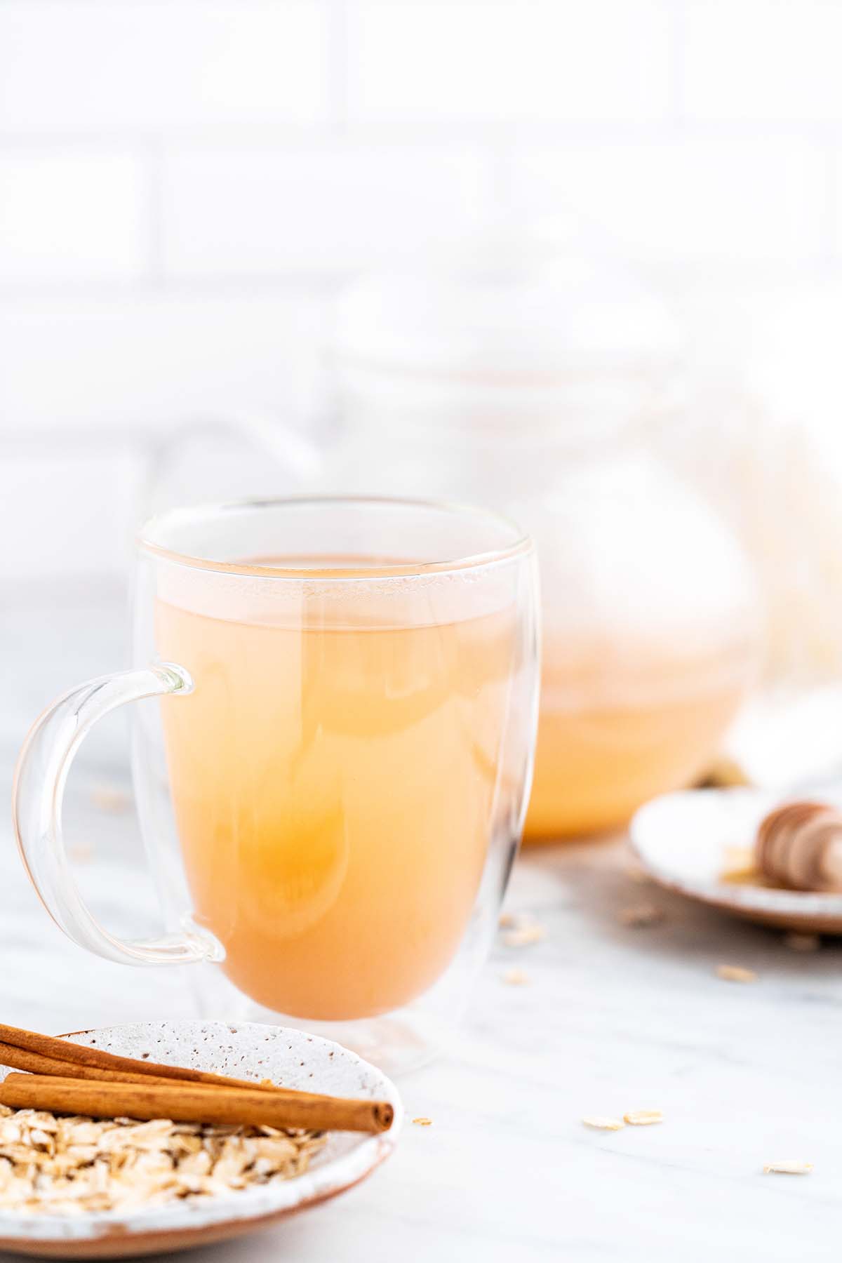 front view of glass mug of hot oat tea on marble countertop