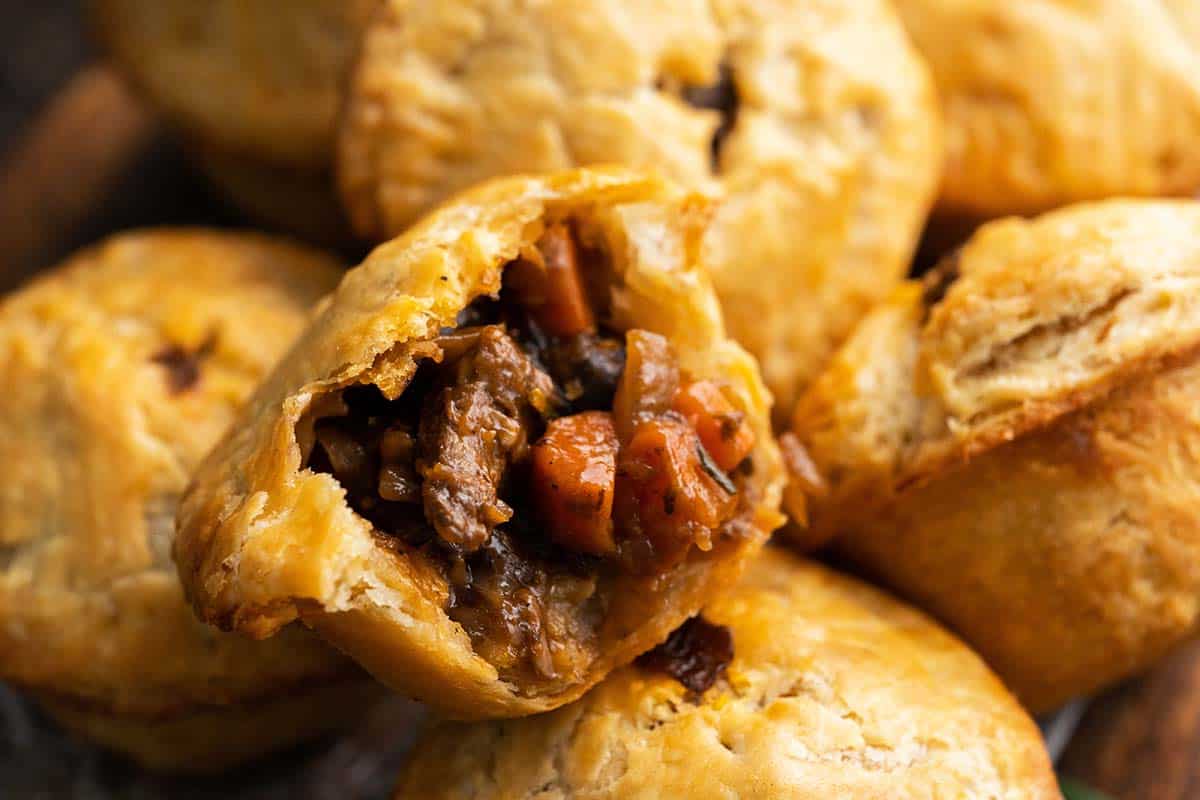 individual steak and ale pie cut in half on stack of pies