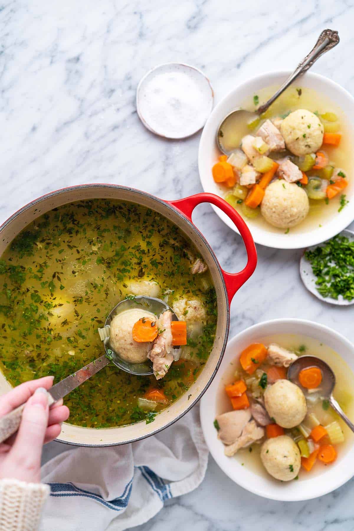 ladling jewish passover matzo ball soup from pot into bowls