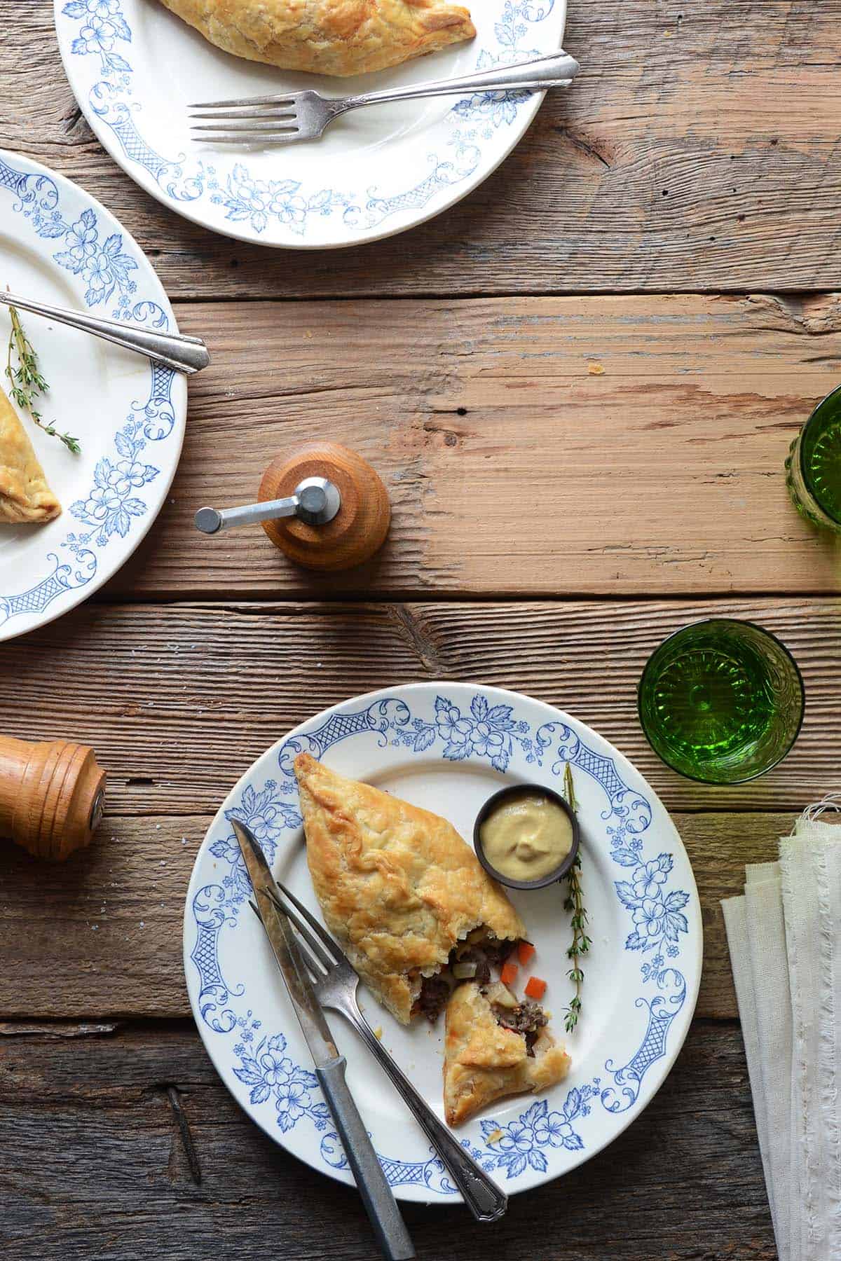 overhead view of cornish pasties on plates on rustic wooden table