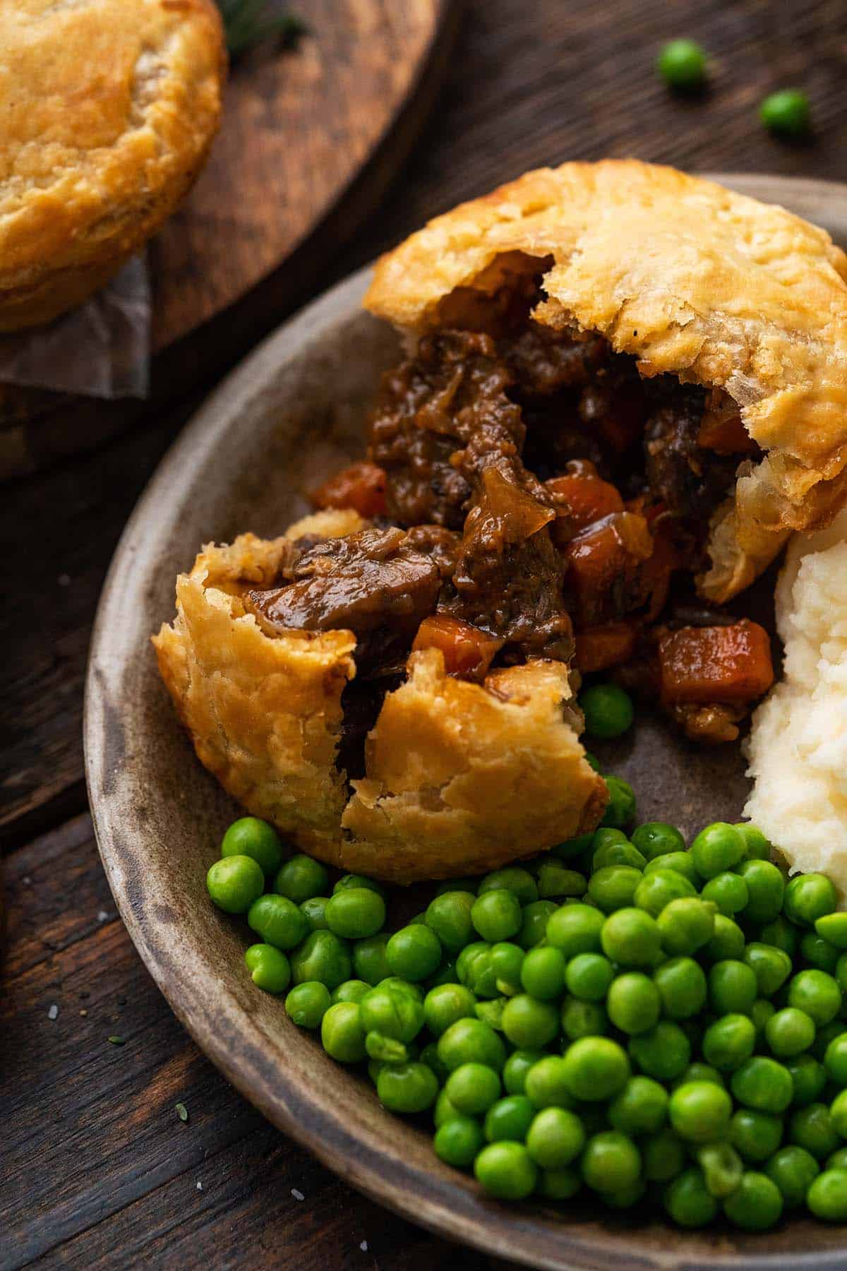 plate with british steak and ale pie meal with mashed potatoes and peas