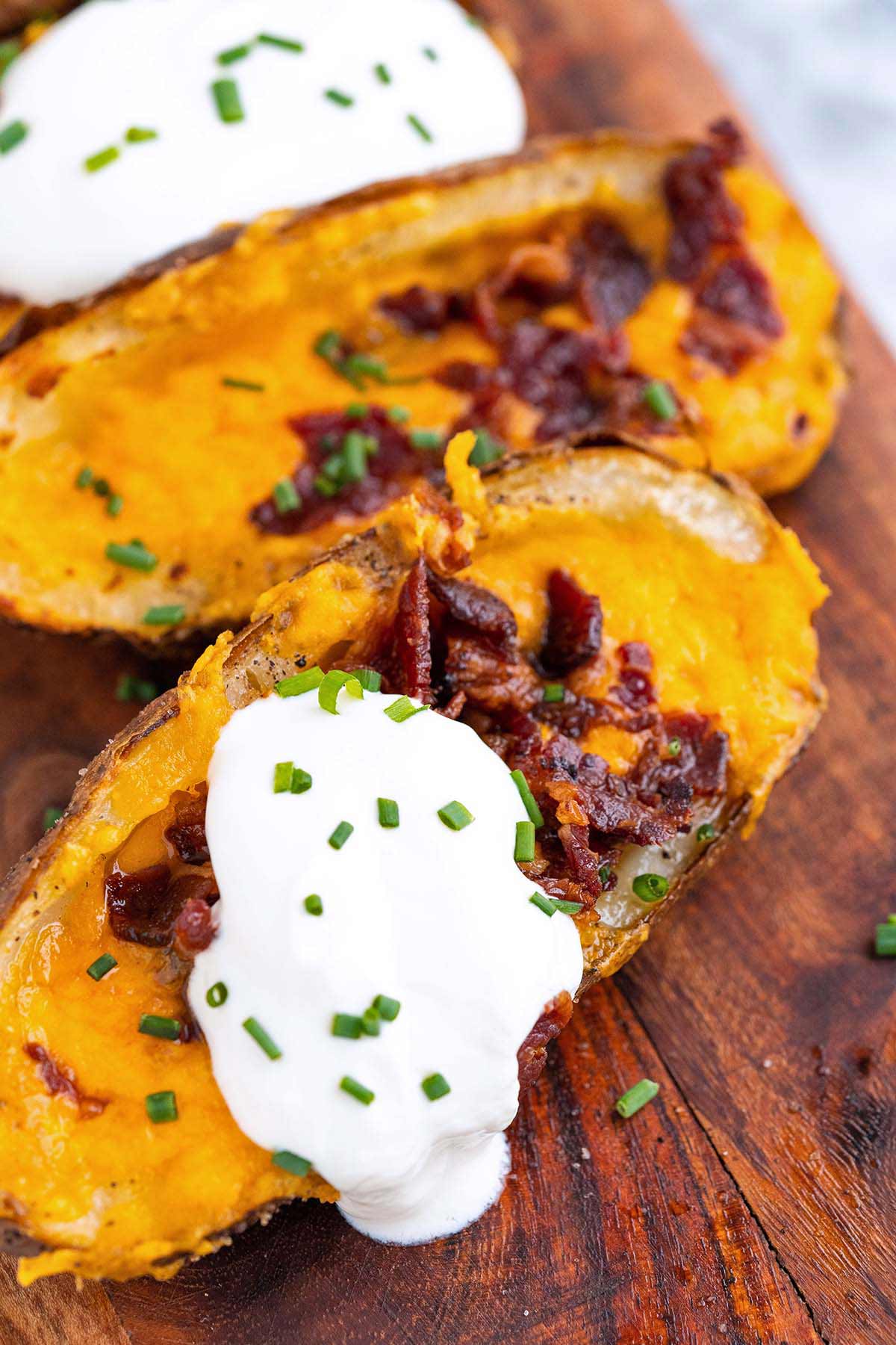 close up front view of crispy potato skins with cheese bacon sour cream and chives