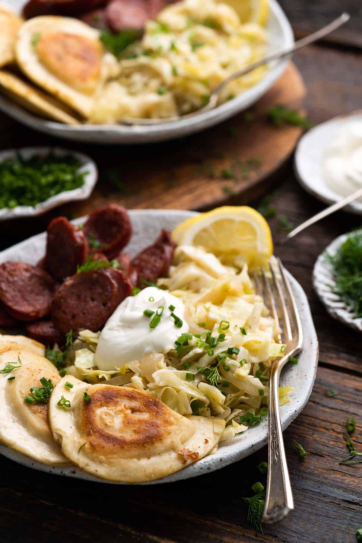 front view of kielbasa and pierogi bowl with cabbage and sour cream