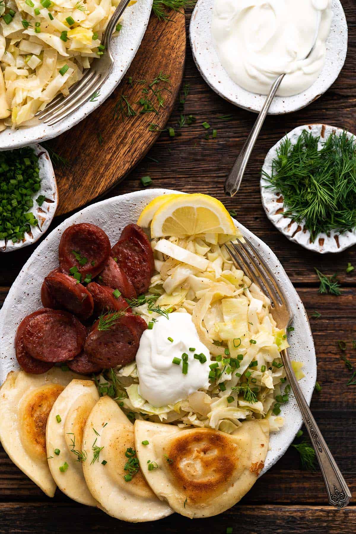 overhead view of pierogies and kielbasa meal in rustic white stonewaare bowl on dark wooden table