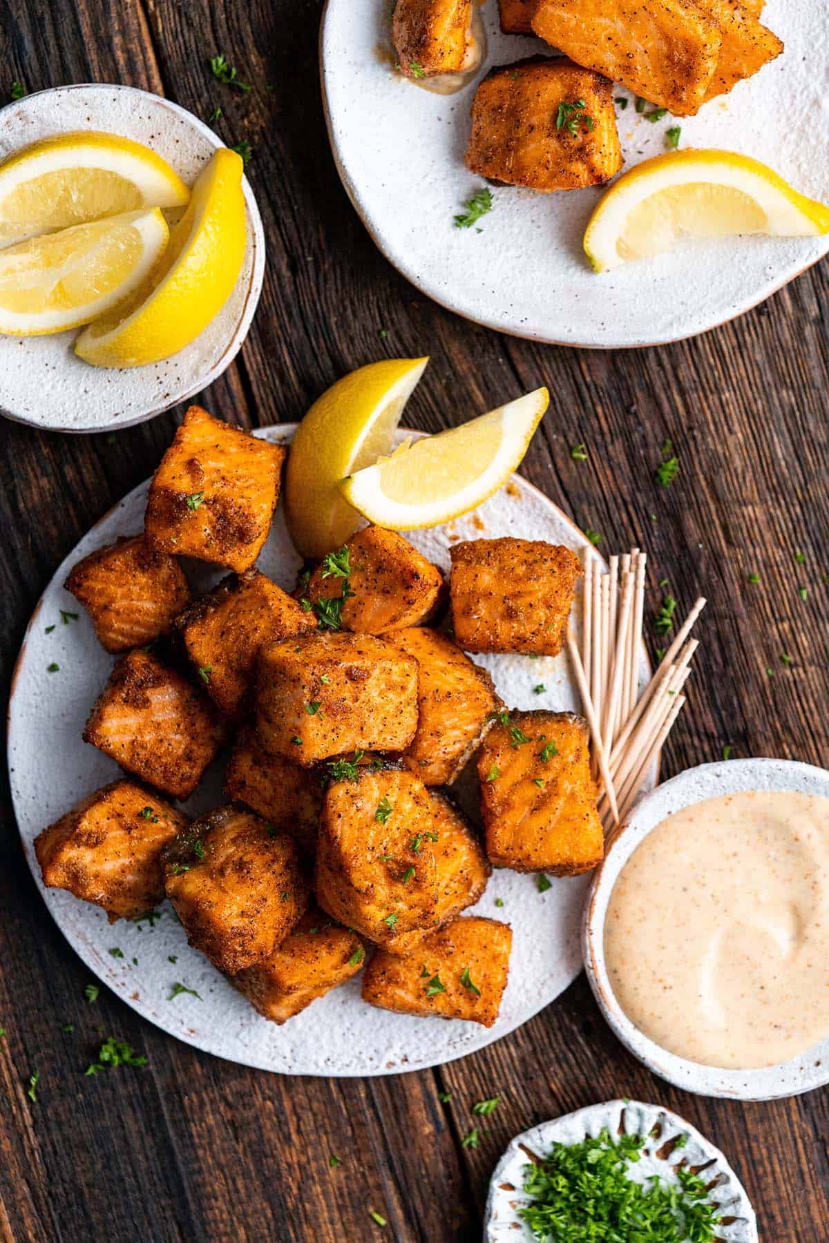 plates with air fryer salmon bites on dark wooden table