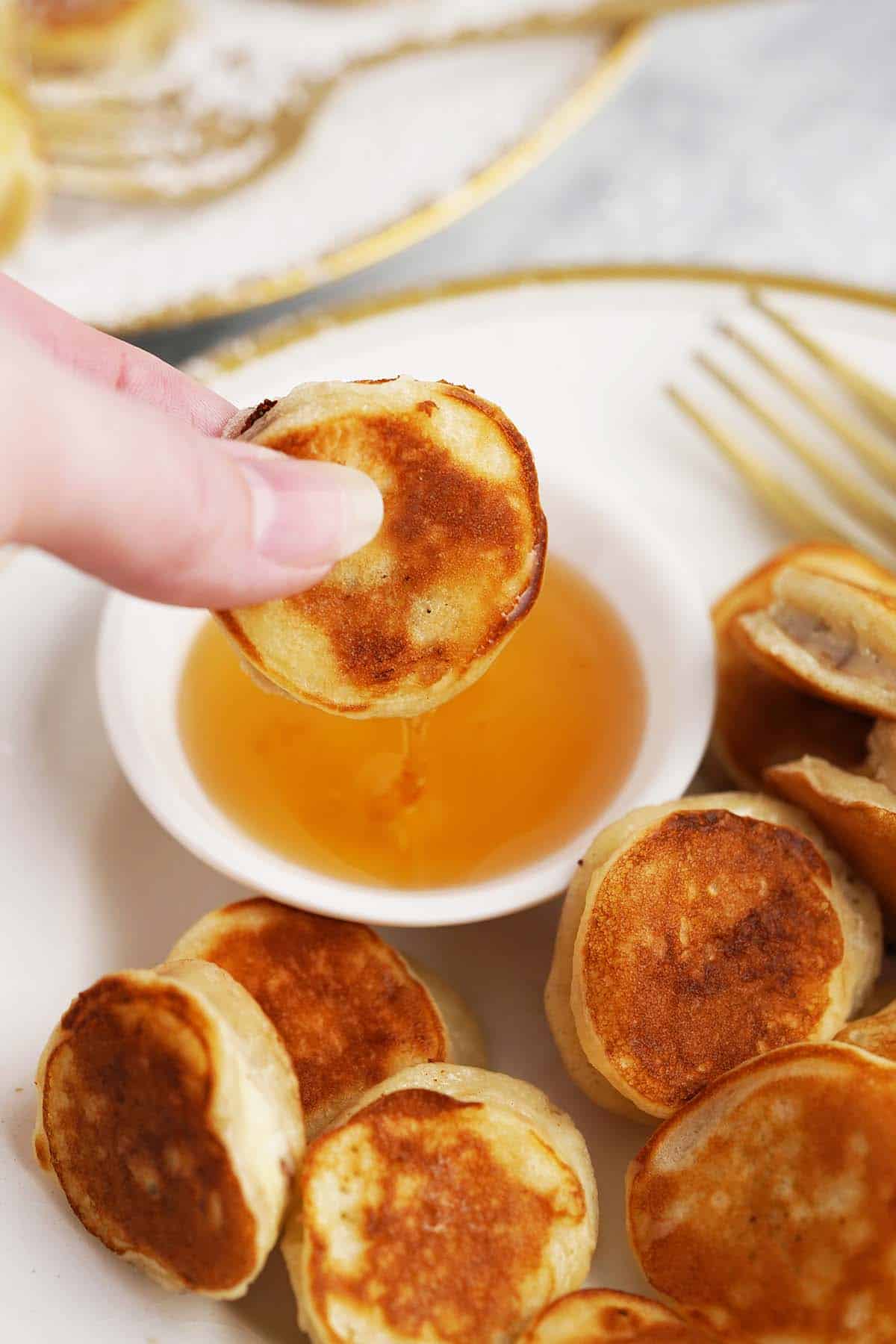 dipping mini banana pancakes into honey and maple syrup