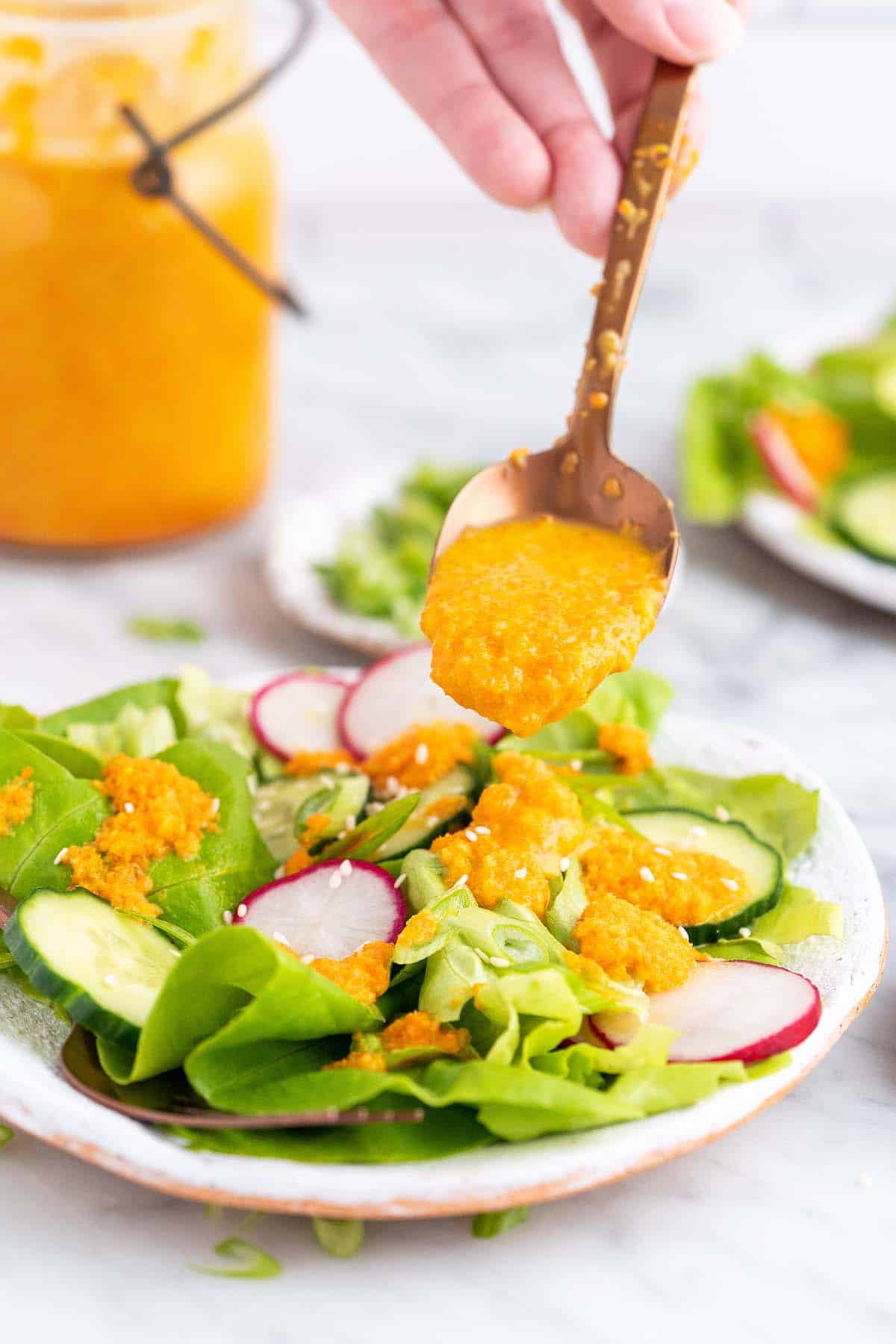 hand adding hibachi ginger dressing on top of lettuce salad