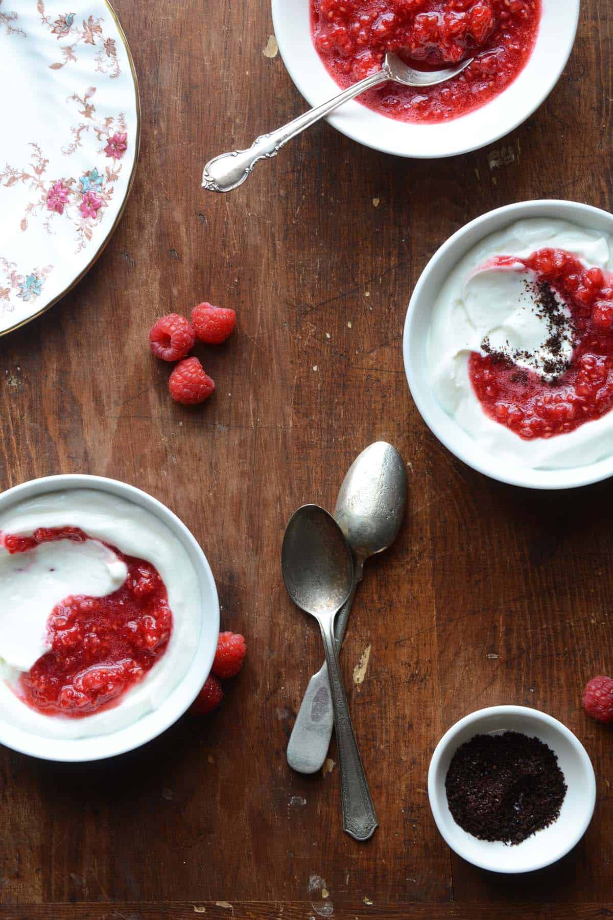 overhead spread of bowls of whipped yogurt with fresh raspberries and raspberry sauce