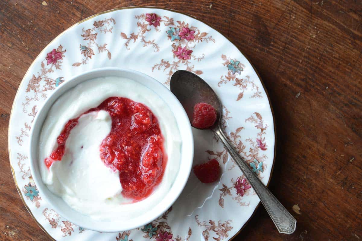 overhead view of whipped yogurt with sumac and fresh raspberry sauce on wooden table