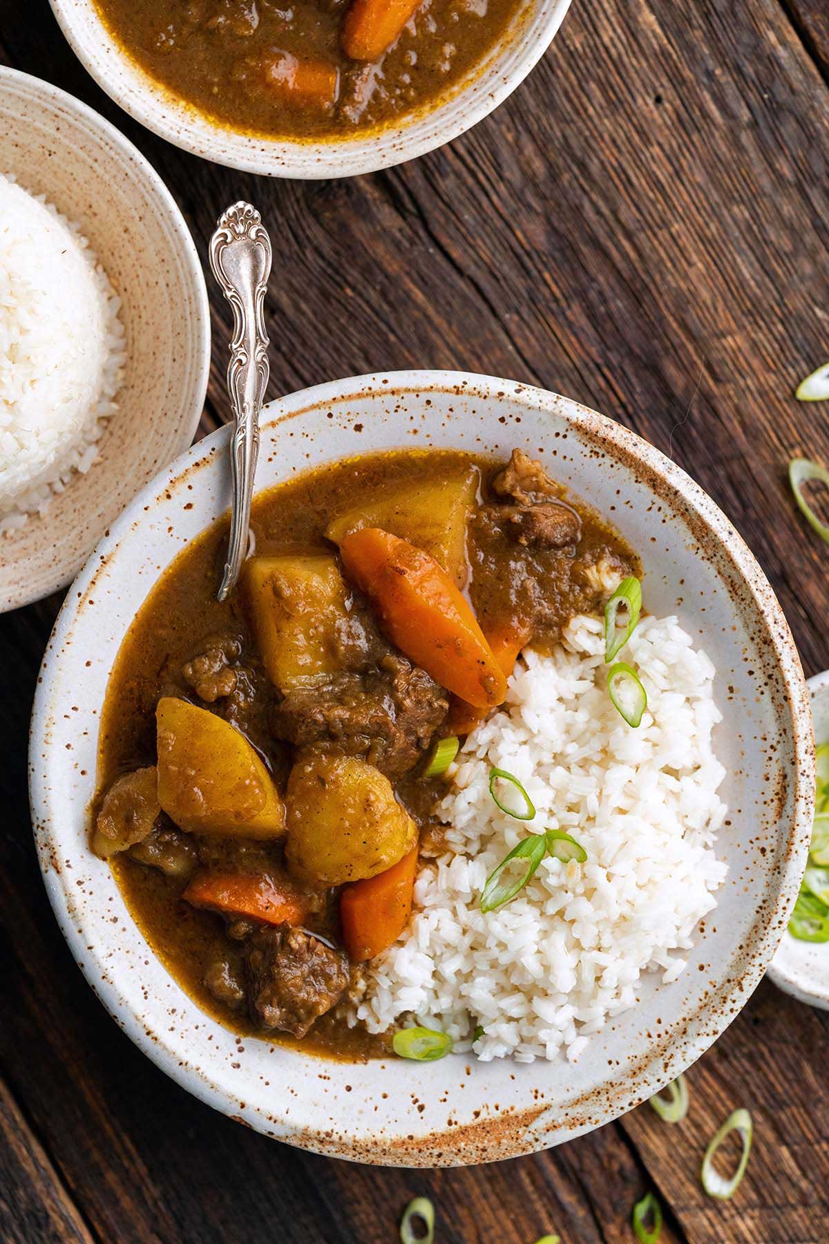 wooden table with bowls of Japanese curry and rice