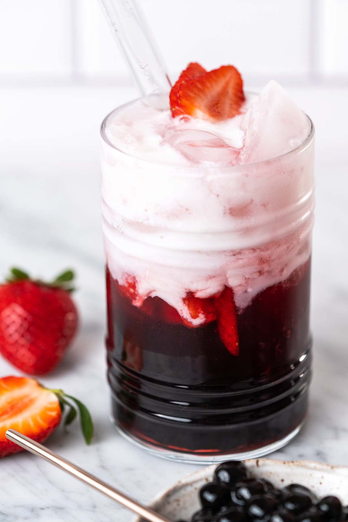 coconut strawberry bubble tea drink in glass on marble countertop