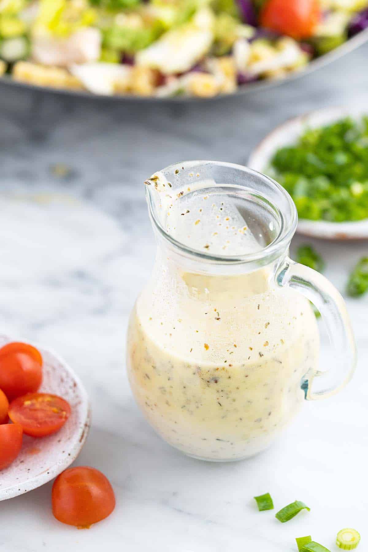 creamy italian dressing with pasta salad in background