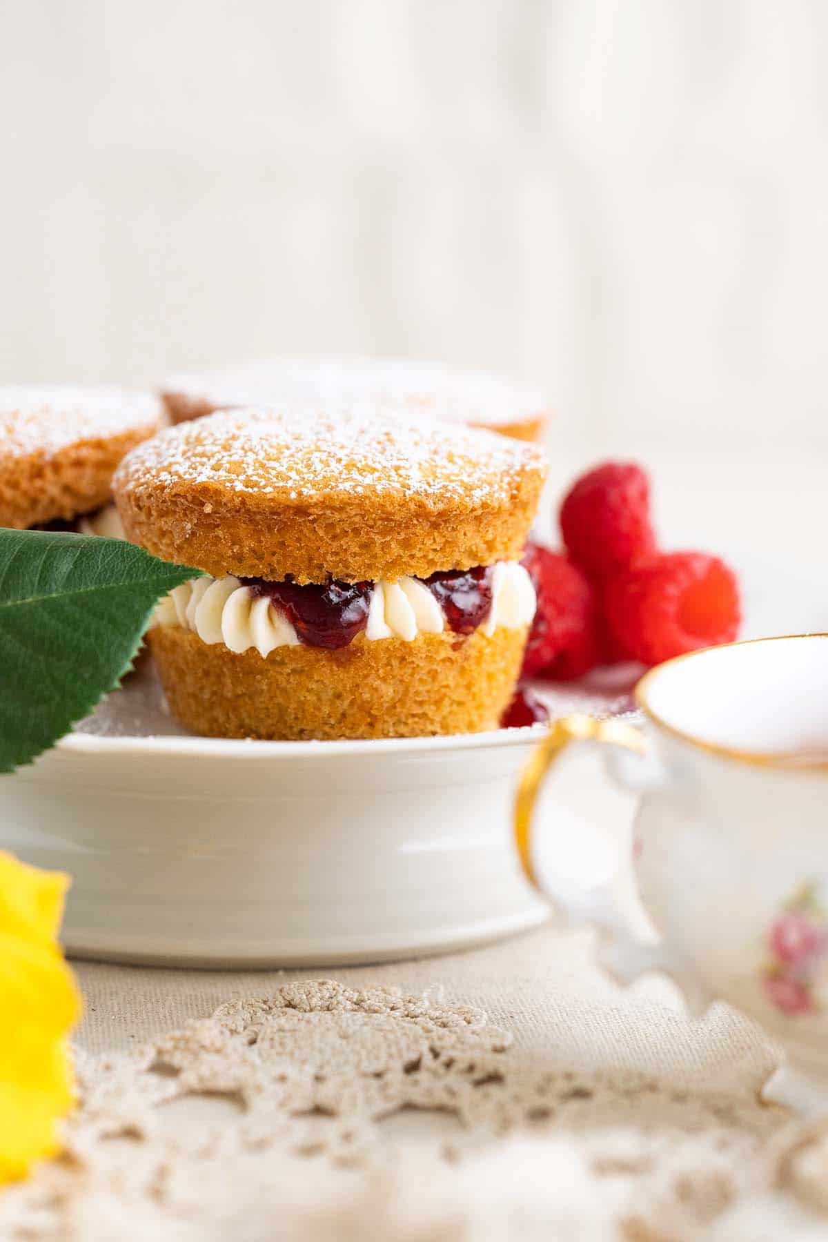 mini victoria sponges on cake pedestal with english teacup in front