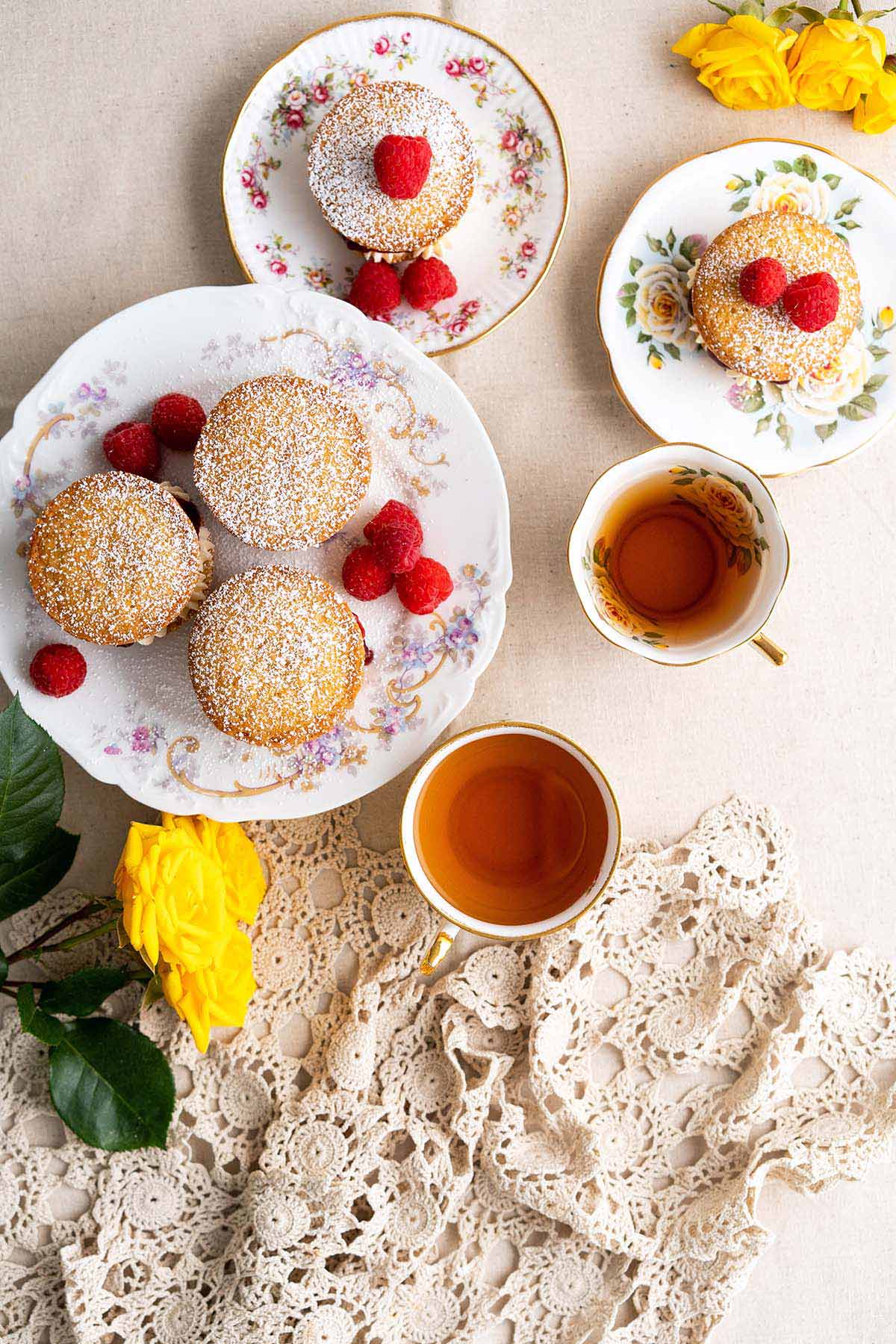 overhead view of table with Victoria sponge cupcakes with tea with yellow roses