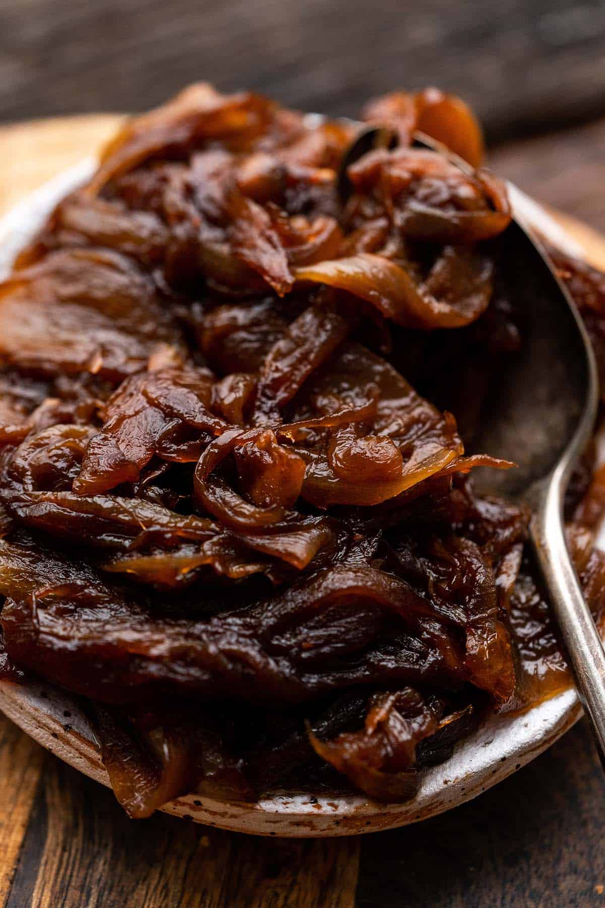 close up of rich caramelized onions in small bowl with spoon