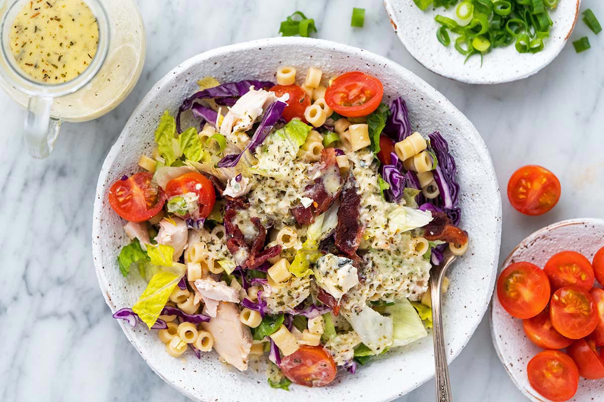 close up top view of Portillo’s chopped salad in stoneware bowl with homemade creamy Italian dressing