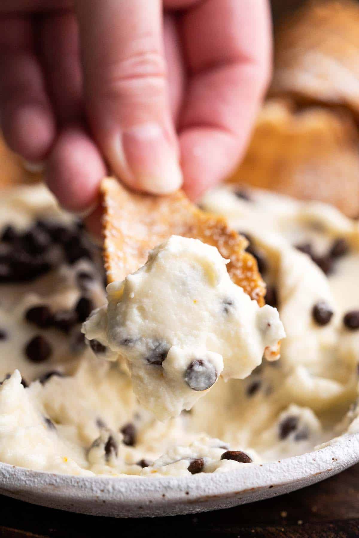 hand dipping chip into homemade cannoli dip