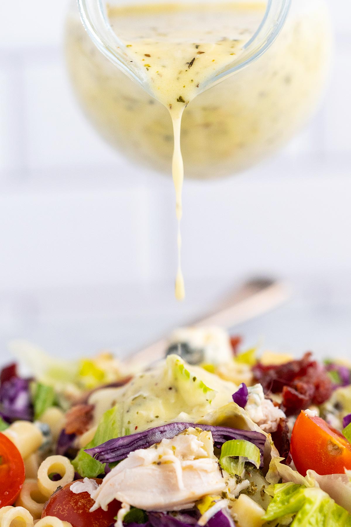 pouring creamy Italian vinaigrette dressing on homemade portillos salad