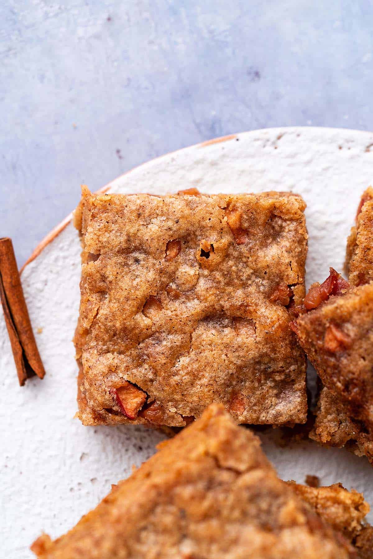 brown butter apple blondies on rustic white plate on blue tabletop