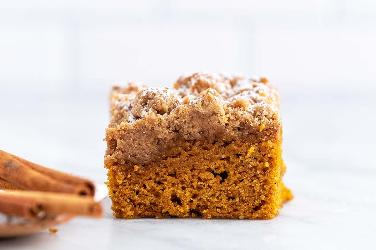 close up front view of square of pumpkin crumb cake on marble countertop