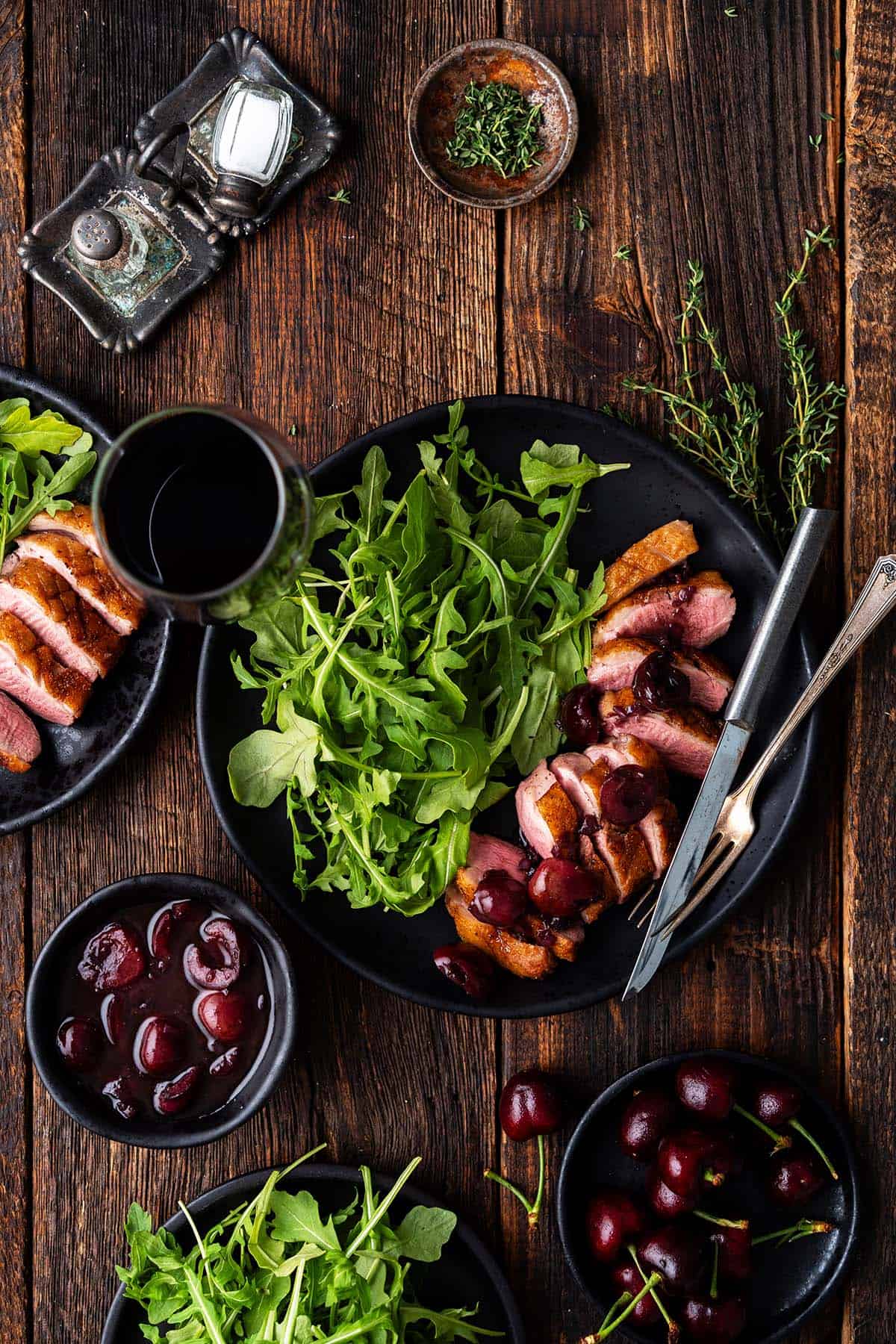 overhead view of duck breast meal with cherry sauce and red wine