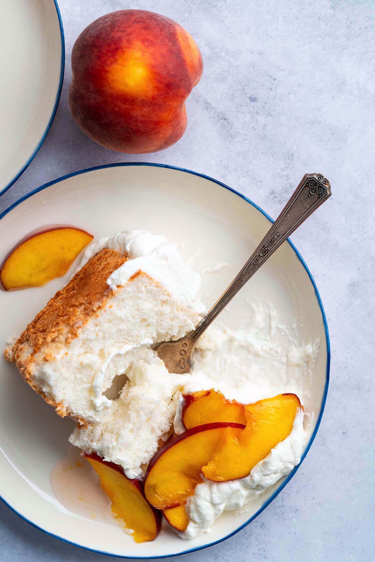 partially eaten angel food cake slice with fresh peach fruit topping