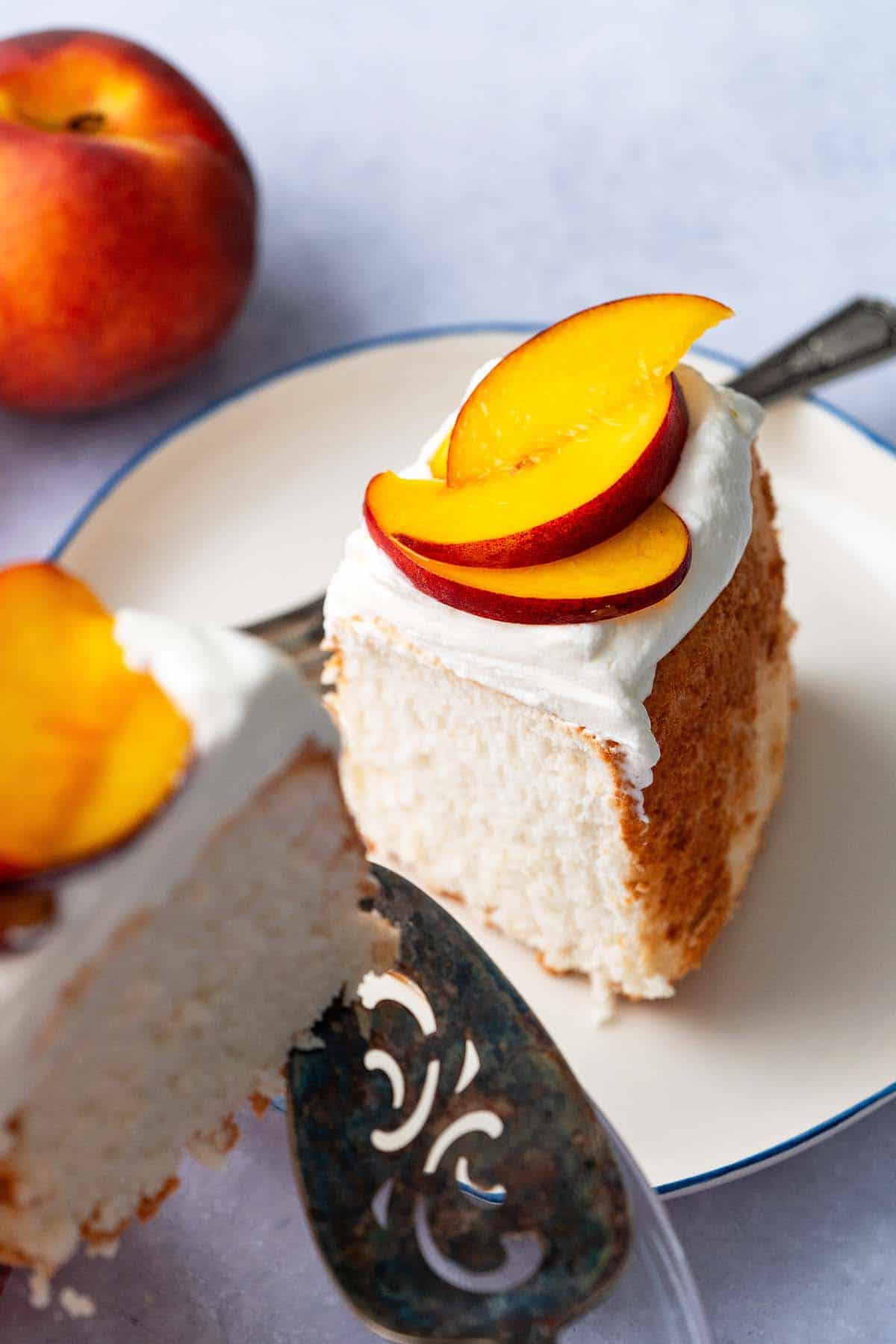slice of angel food cake on individual plate with peaches and cream on top