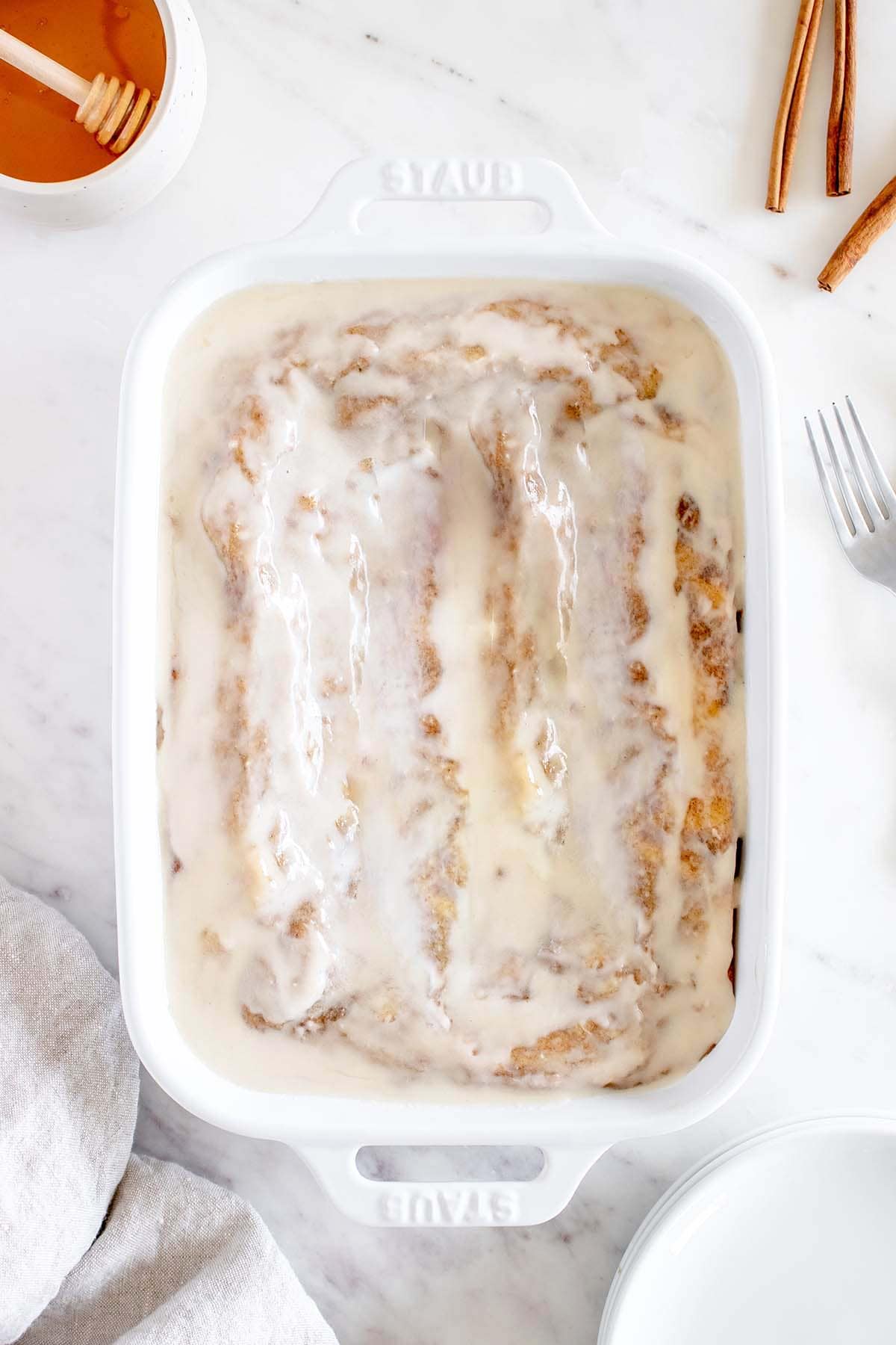 top view of whole honey bun cake with icing in baking dish